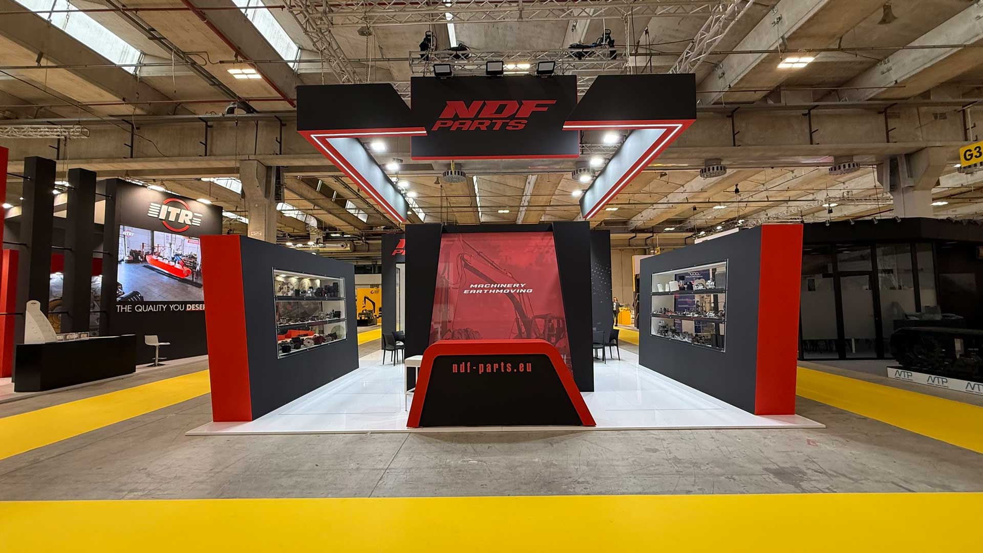 Prospetto frontale dell'allestimento stand NDF Parts con grafiche dedicate alle macchine movimento terra e teche espositive.